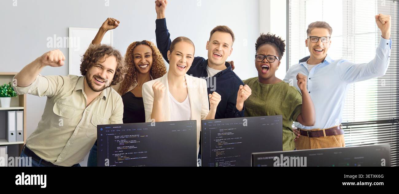 Happy diverse developers team cheering in office after coding project success Stock Photo