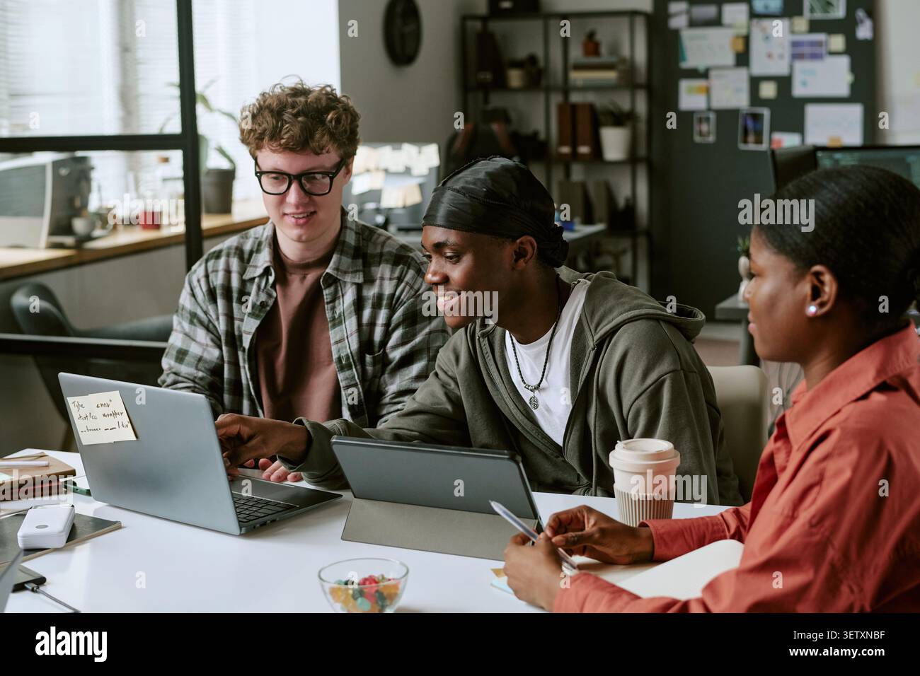 Diverse Colleagues Collaborating on Laptop in Creative Workspace Stock Photo