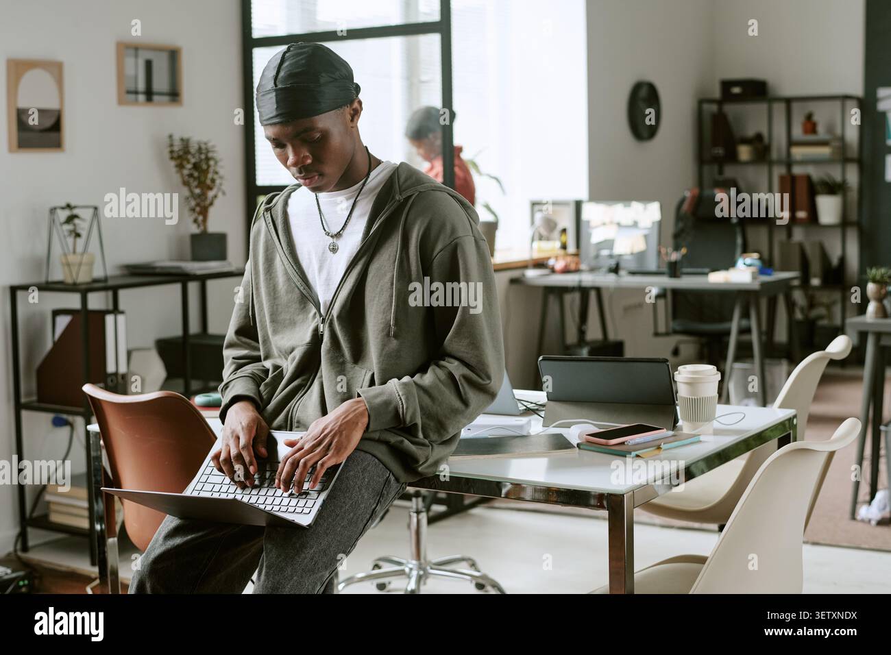Black Man Working on Laptop in Modern Shared Office Stock Photo