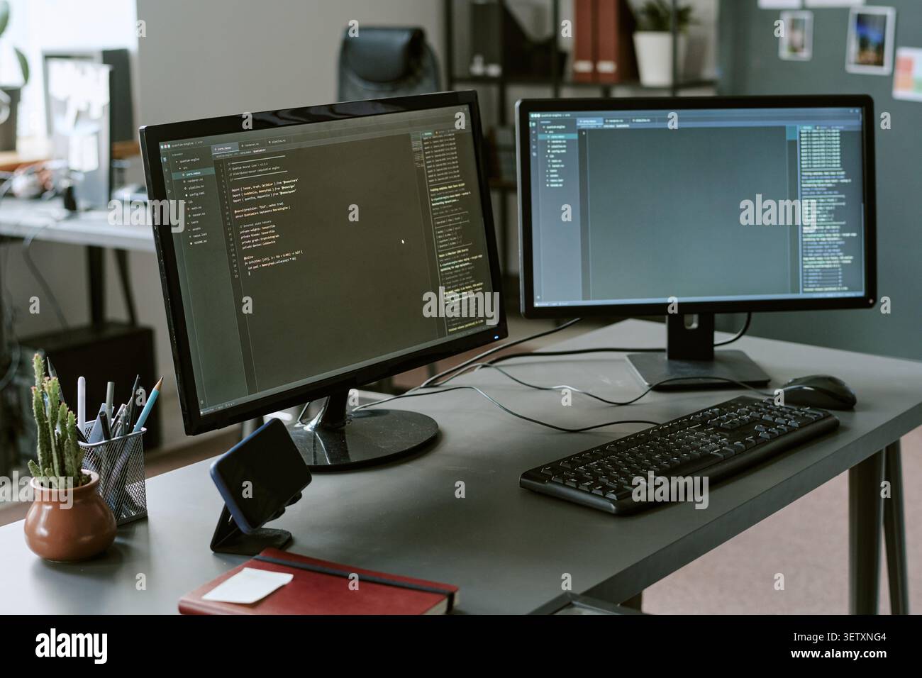 Dual Monitors Displaying Software Code in Modern Office Workspace Stock Photo