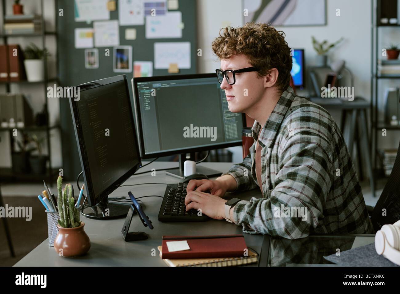 Adult Man Coding at Dual Monitors in Software Development Office Stock Photo