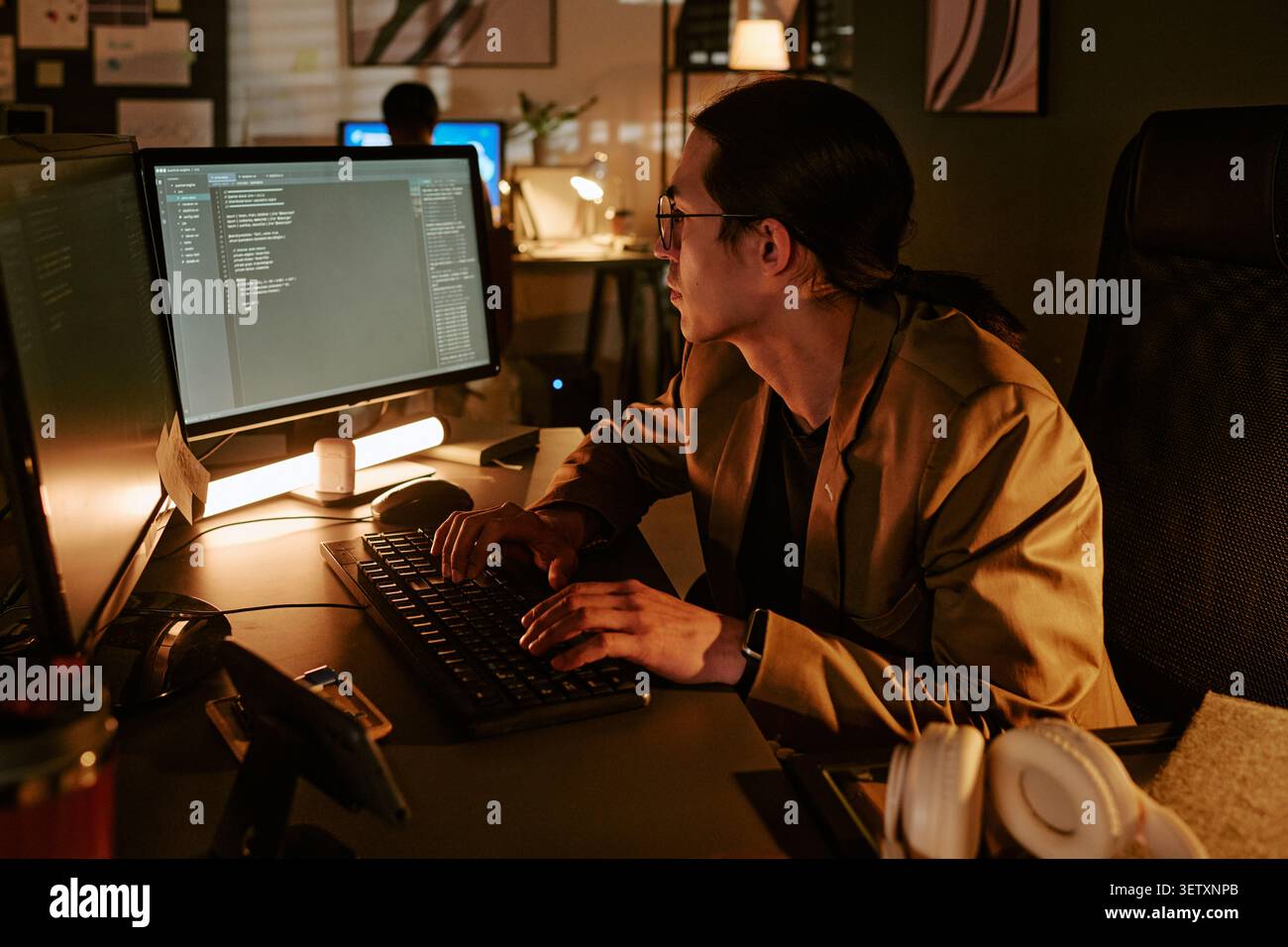 Asian Man Coding at Computer during Night Shift in Office Stock Photo