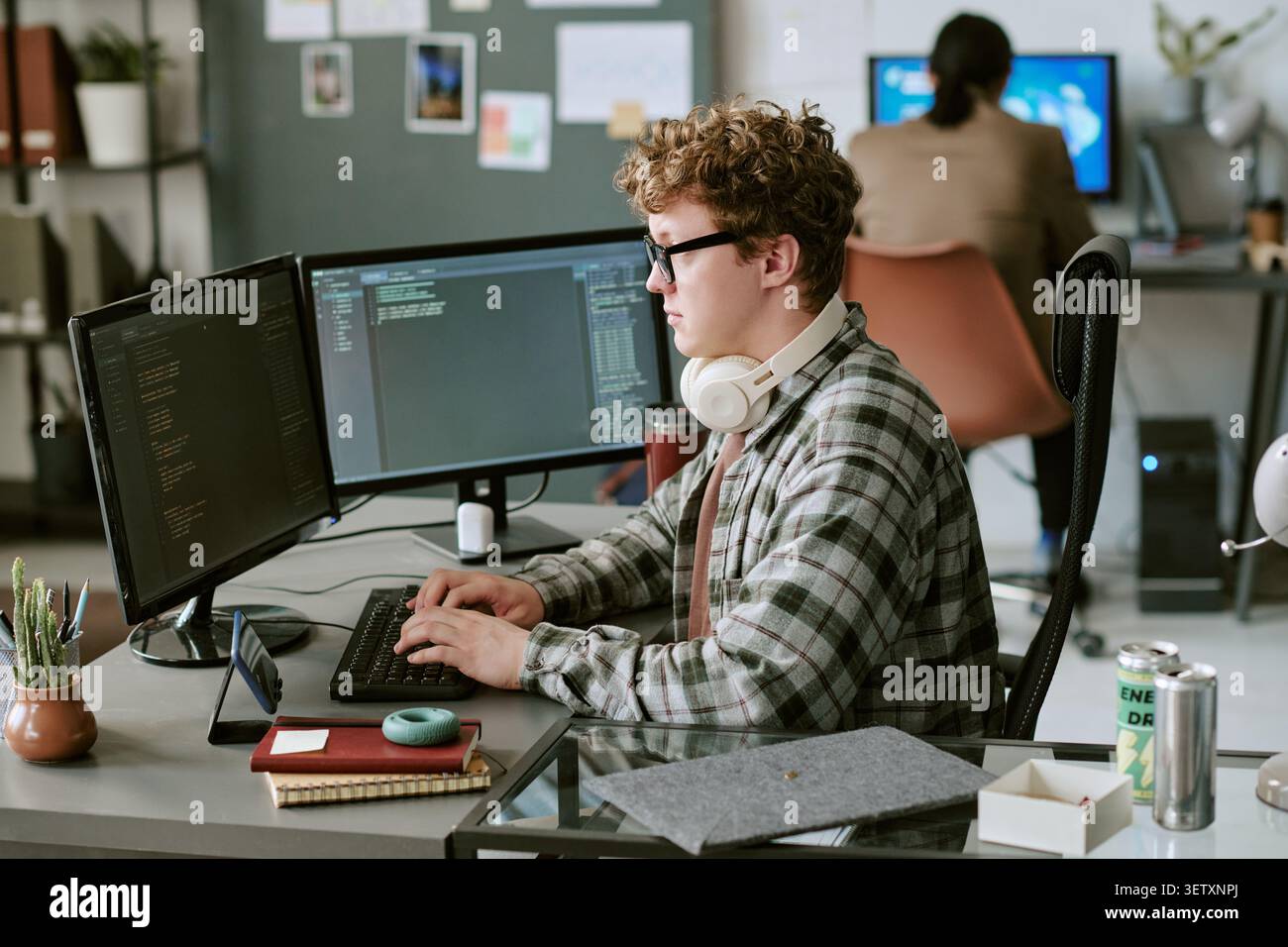 Man Typing Code at Dual Monitors in Shared Office Stock Photo
