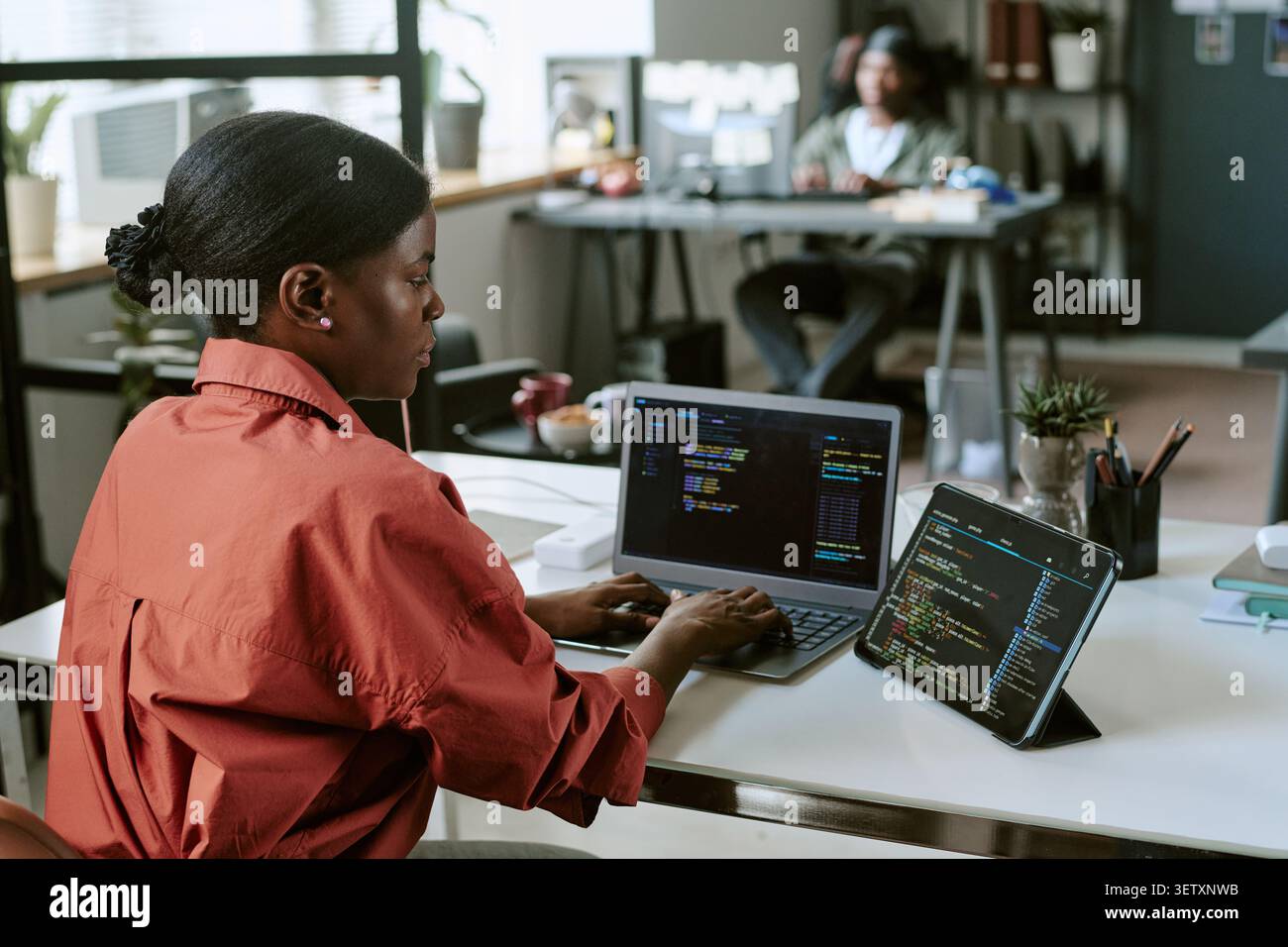 Black Woman Developer Coding on Laptop in Modern Office Stock Photo