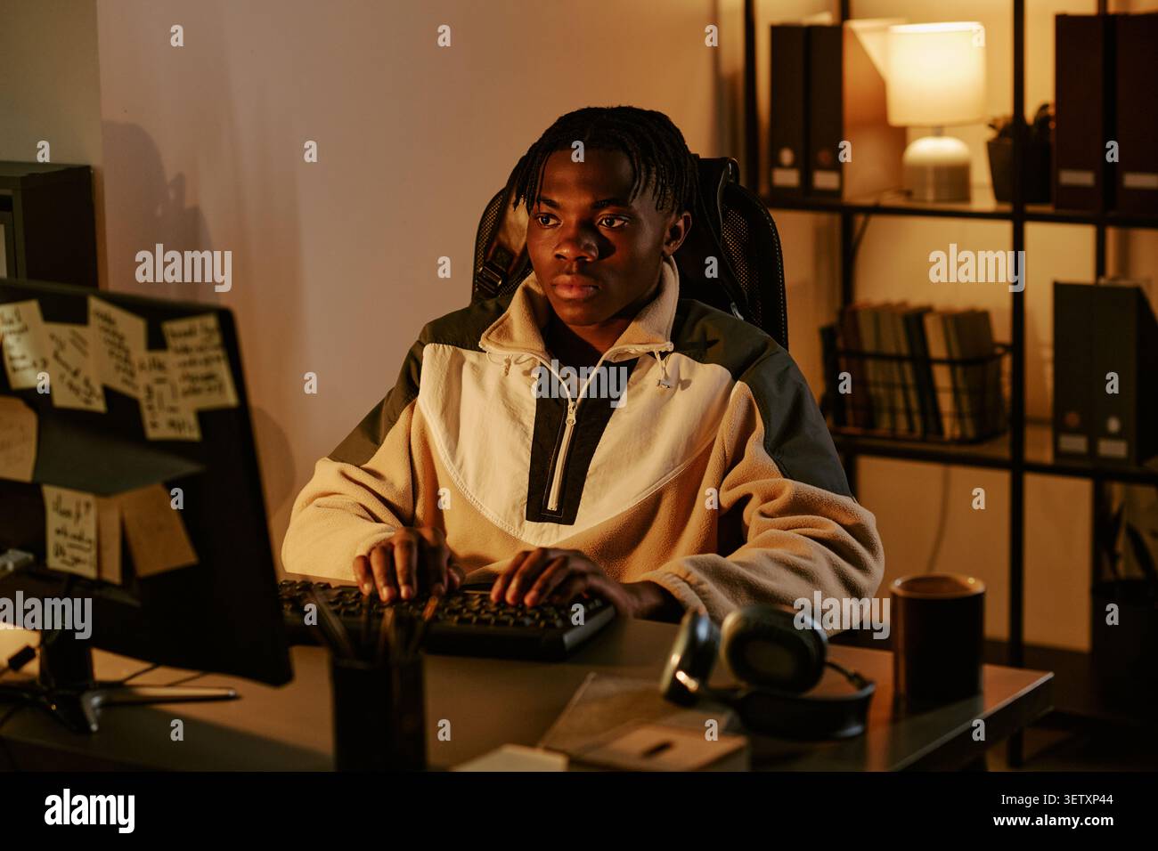 Black Man Working on Computer in Office at Night Stock Photo