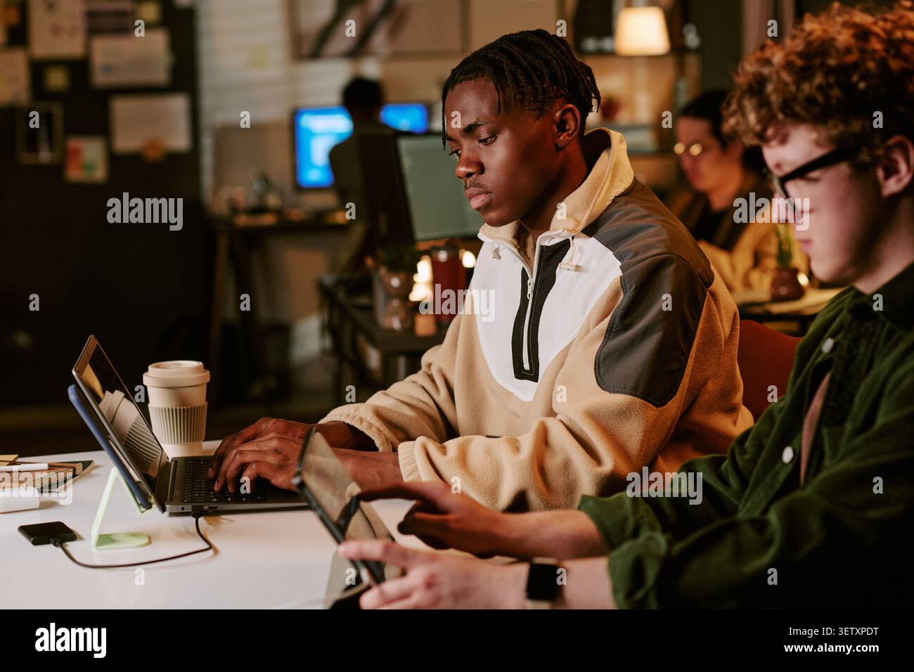 Black Man Working on Laptop in Collaborative Startup Office Stock Photo