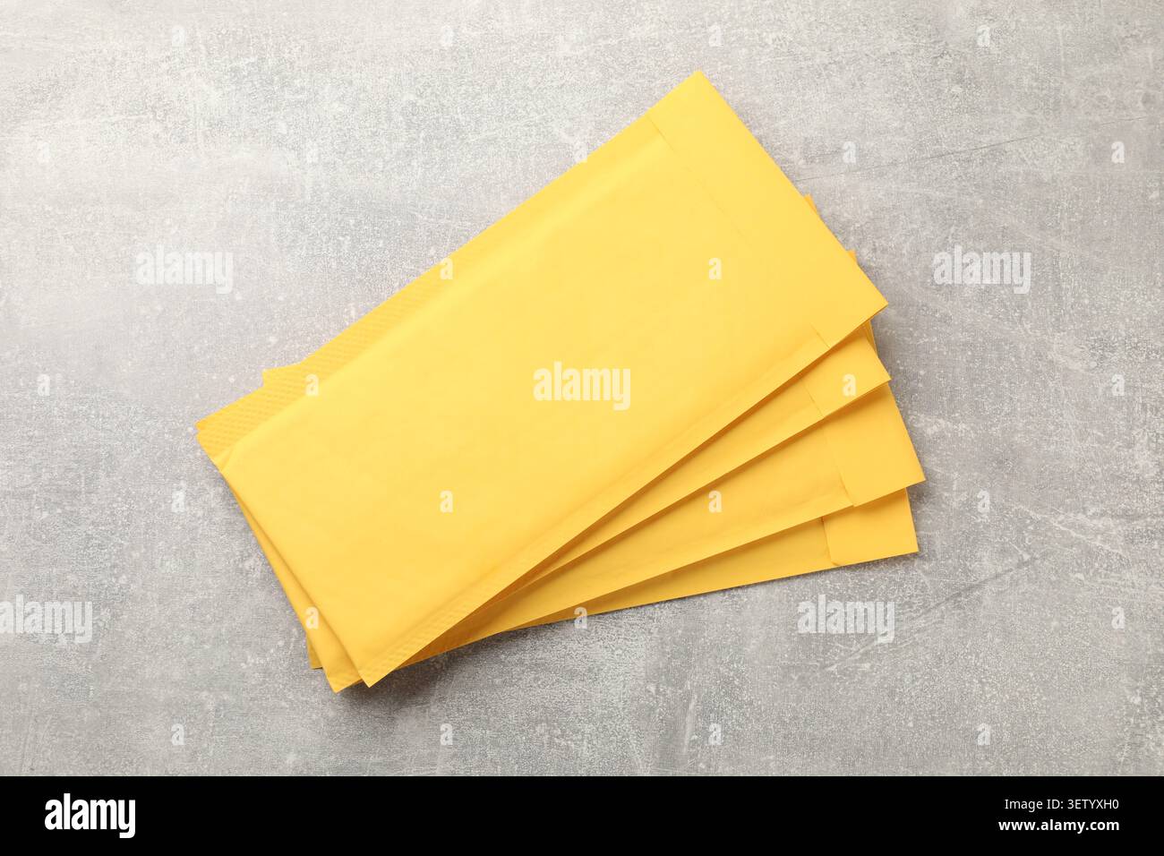 Stack of yellow envelopes on grey table, top view Stock Photo