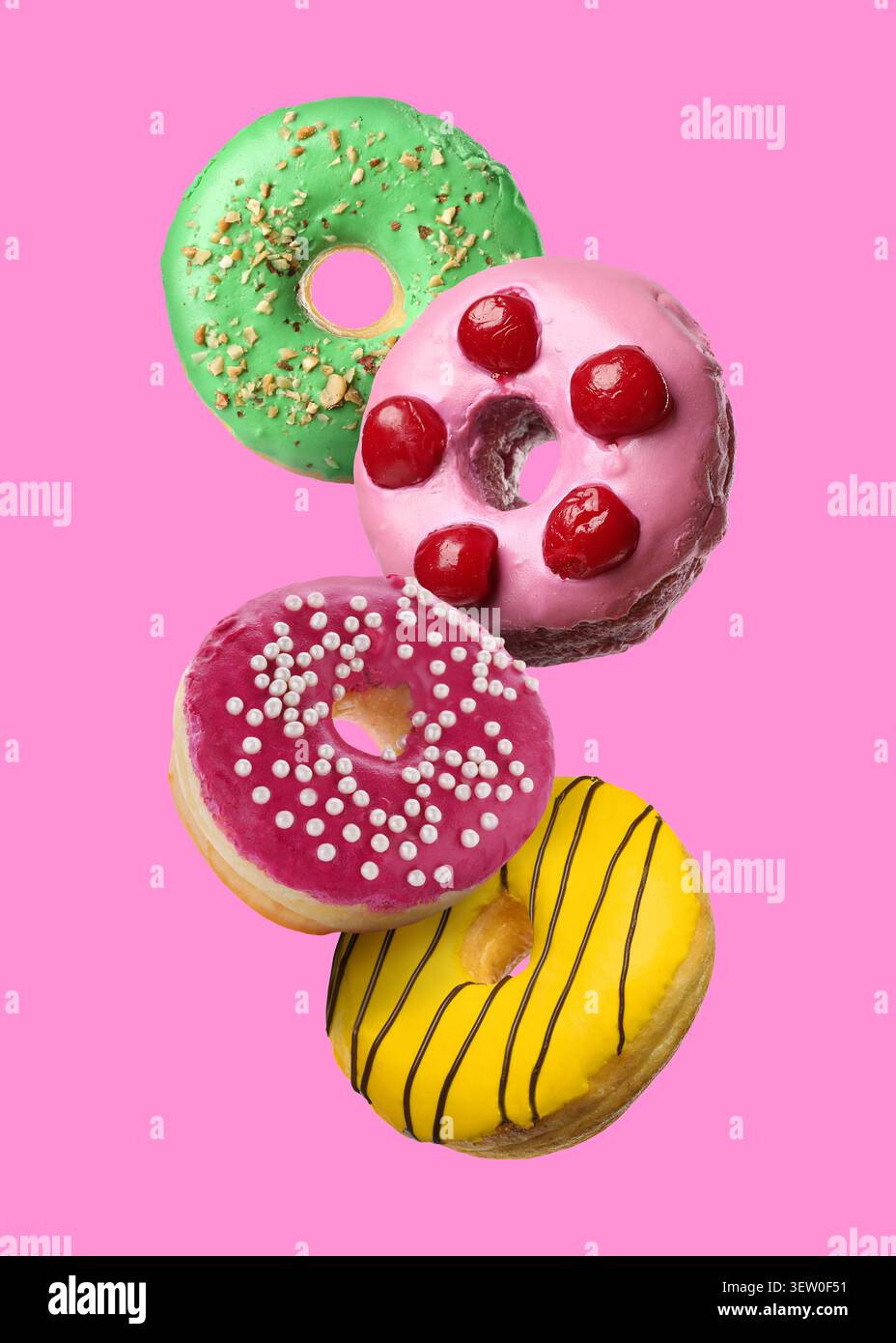 Yummy donuts covered with icing falling on pink background Stock Photo