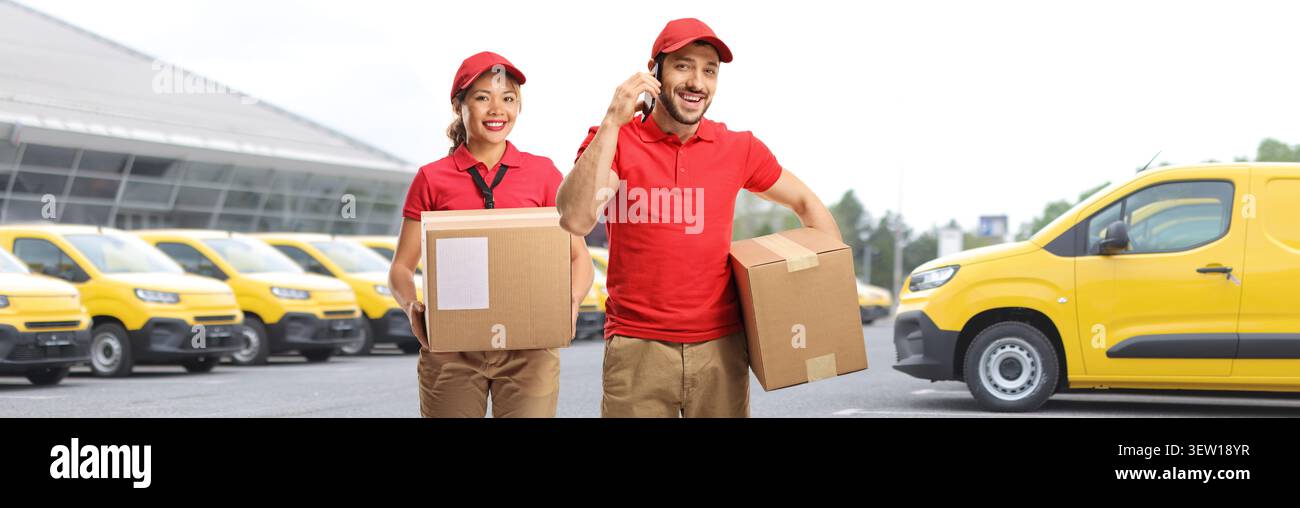 Delivery workers holding packages with vans in the background Stock Photo