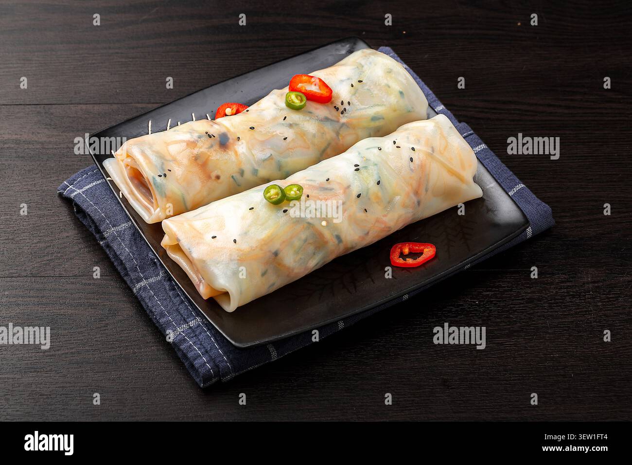 Yunnan style fresh rice sheets wrapped with mixed vegetables on a black square plate Stock Photo