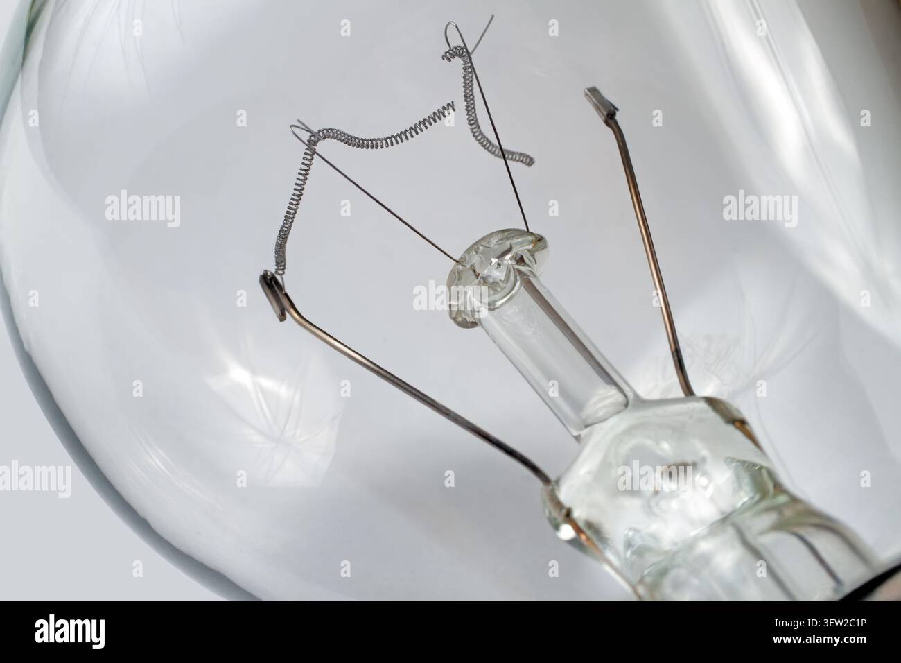 Burned-out incandescent light bulb on a gray background. Burnt tungsten filament close-up. Stock Photo