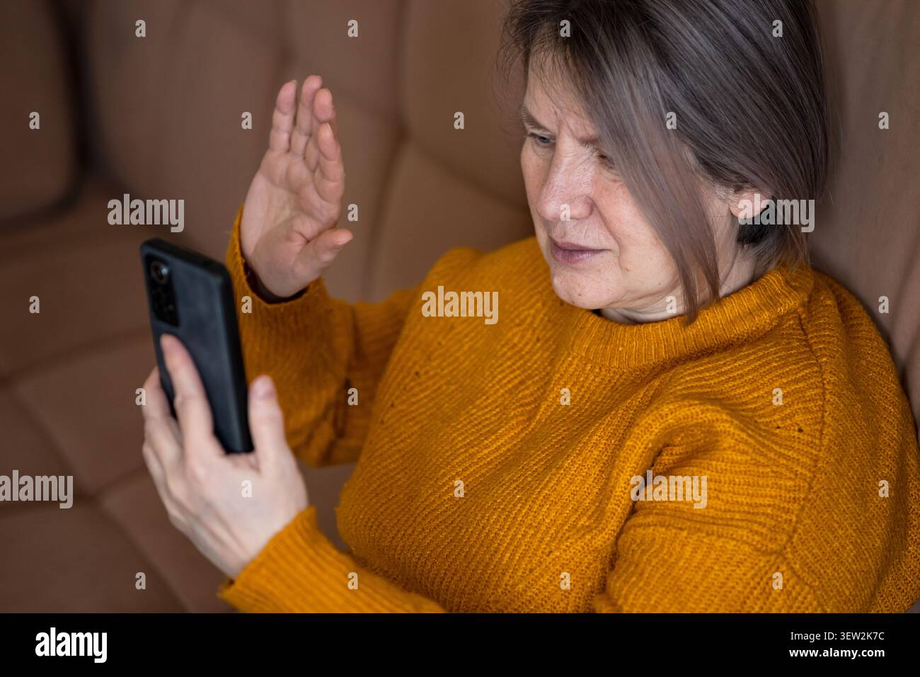 Mature woman having video call on smartphone, waving hand Stock Photo