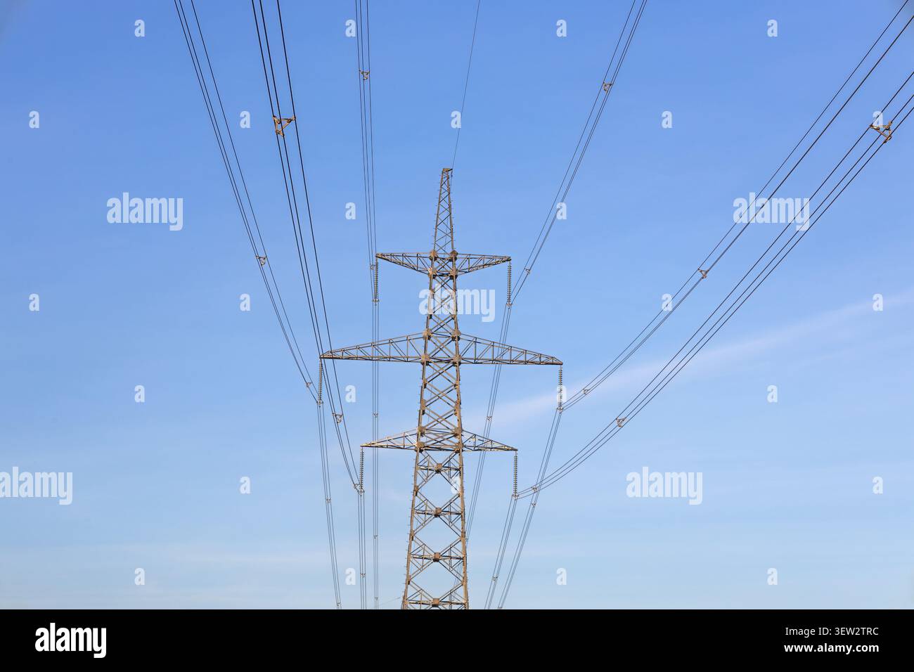 High voltage power transmission tower against blue sky Stock Photo