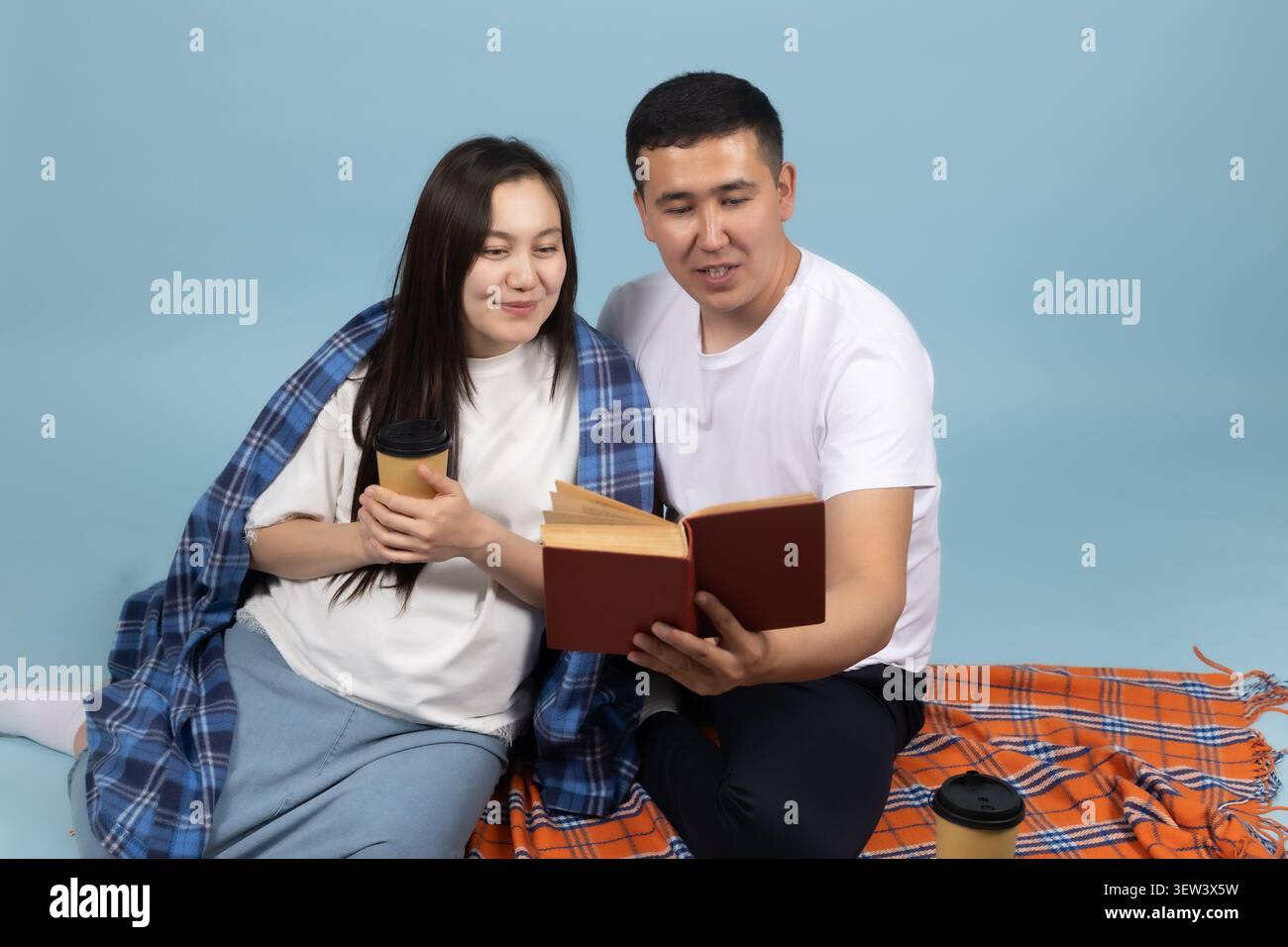 Happy young couple reading an interesting book together at home picnic Stock Photo