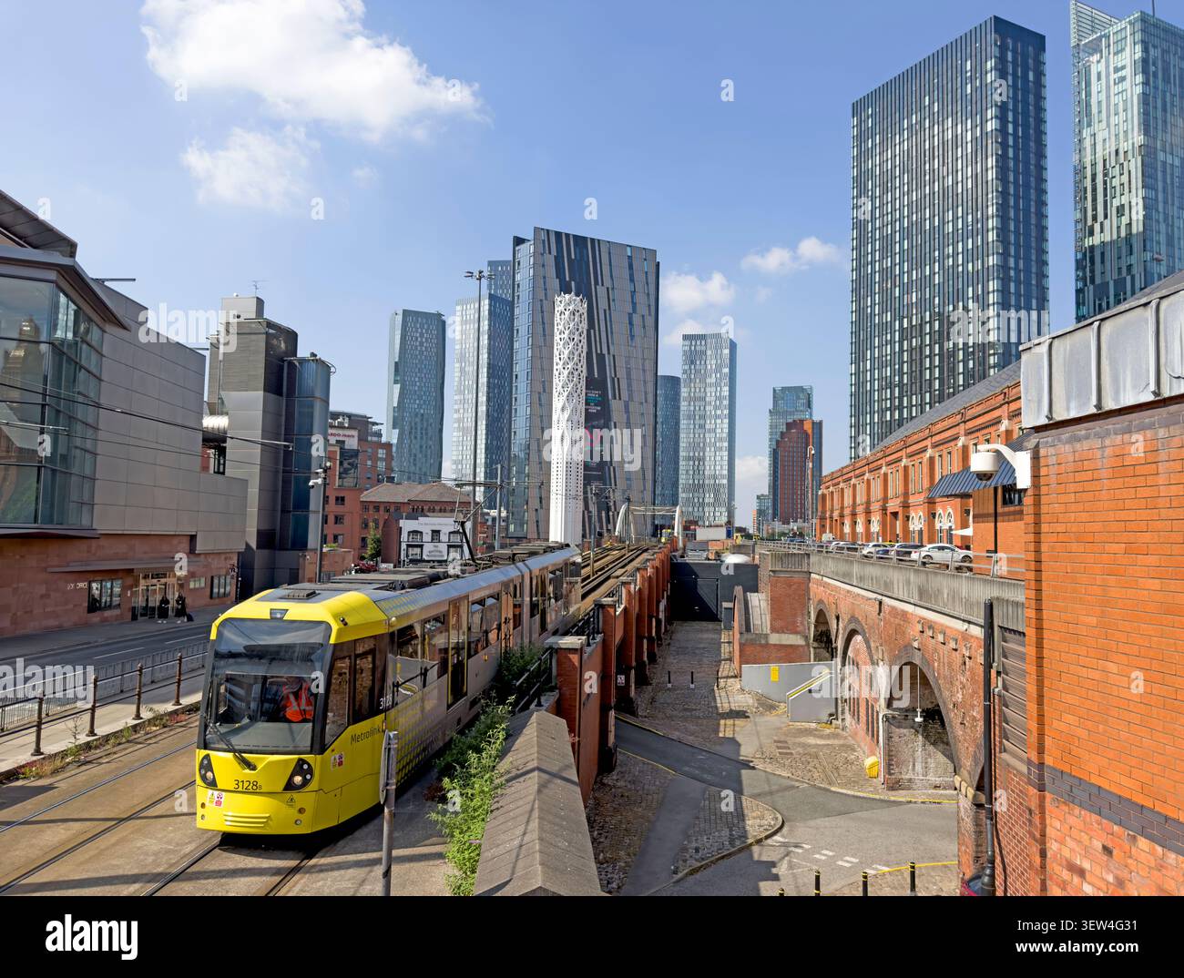 A yellow Manchester Metrolink tram emerges at Deansgate-Castlefield with new Manchesterism high-rise apartment skyline blocks behind. Stock Photo