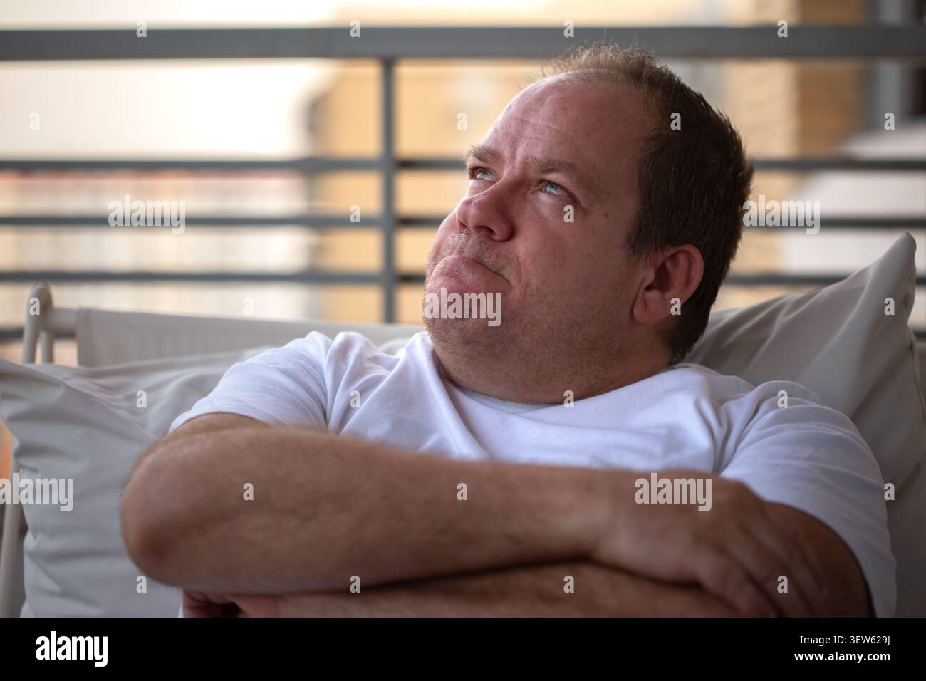 Thoughtful middle-aged man sitting on sofa looking away in contemplation Stock Photo