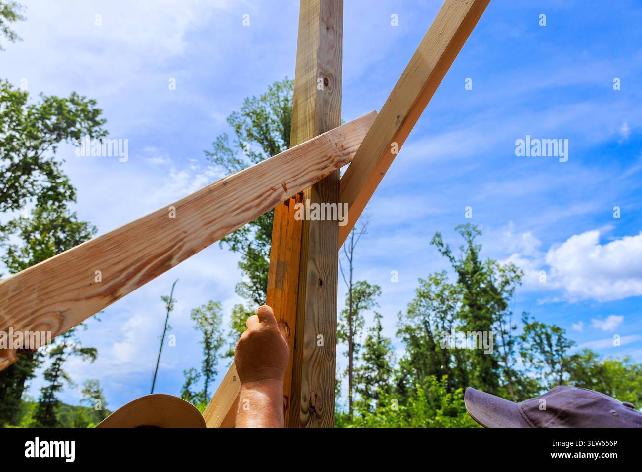 Two workers are engaged in construction, using level tool with wooden beams Stock Photo