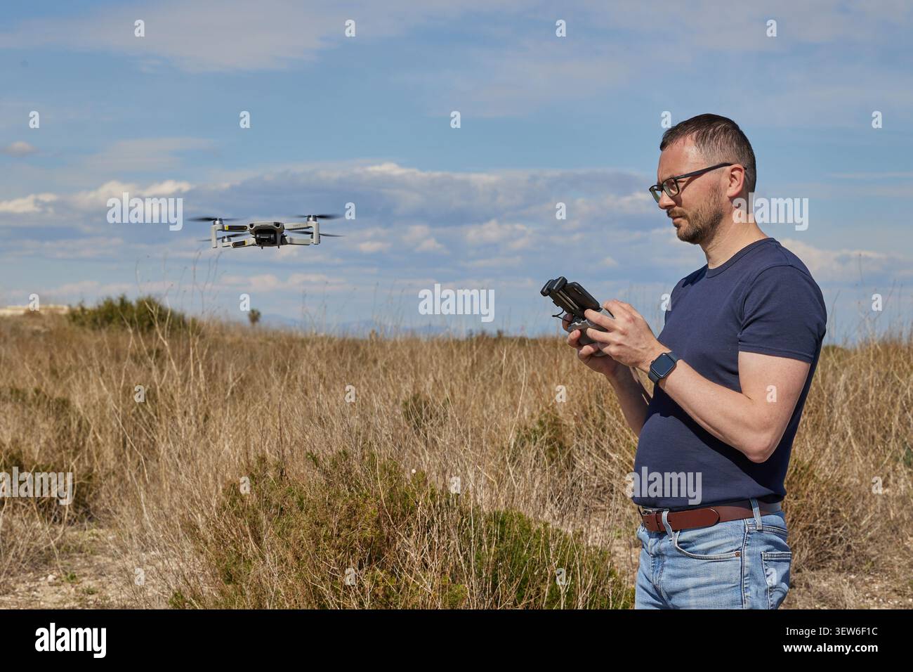 A handsome man controls a quadcopter in a field Stock Photo