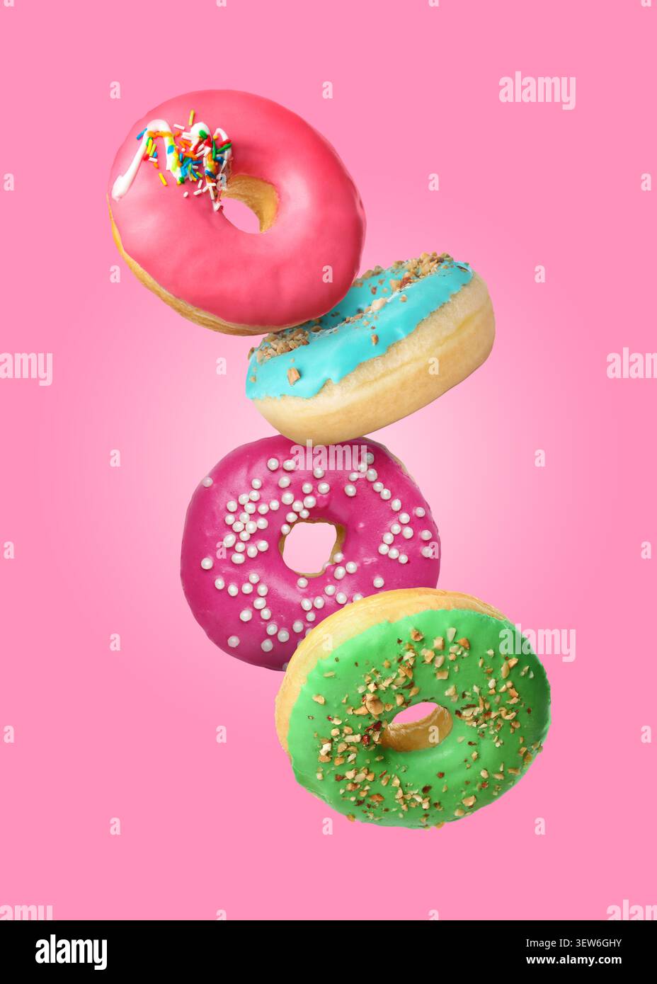 Yummy donuts covered with icing falling on pink background Stock Photo