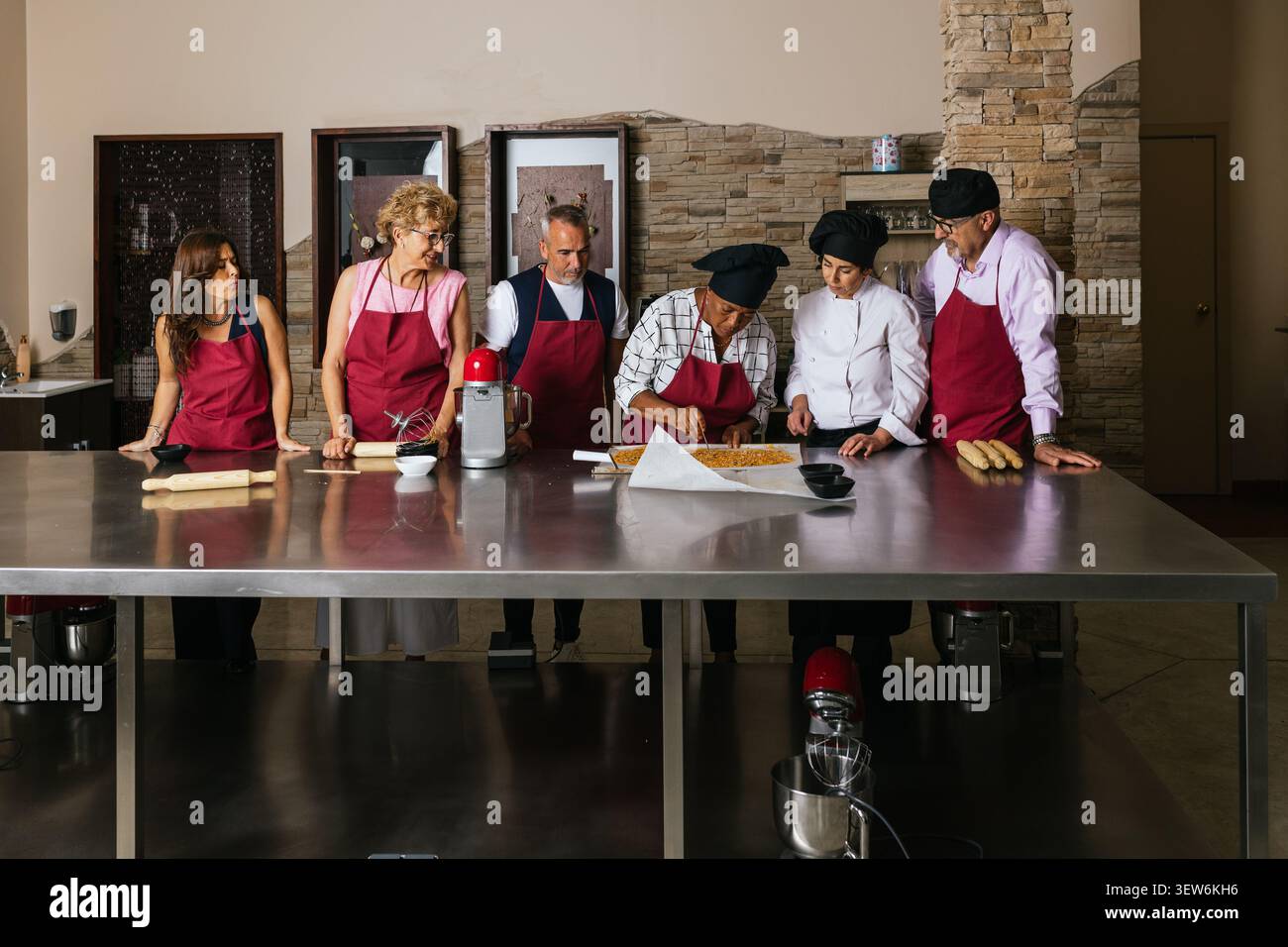 Chefs and students preparing food in restaurant kitchen during cooking course Stock Photo