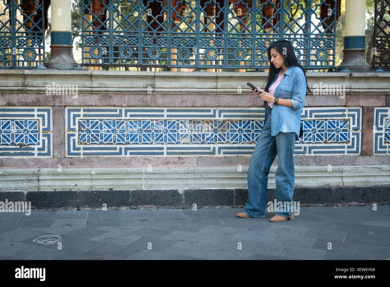 Woman using smartphone by kiosco morisco wall Stock Photo