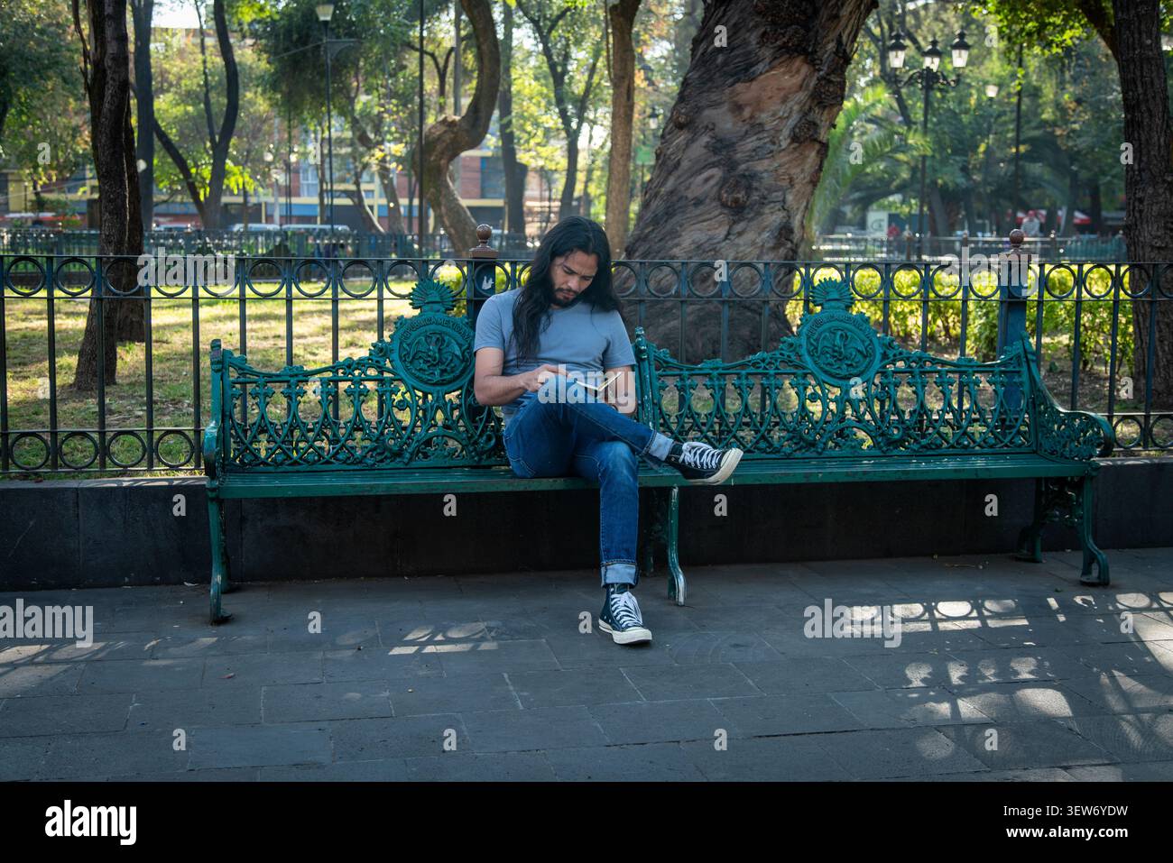 Young man reading book relaxing on park bench Stock Photo