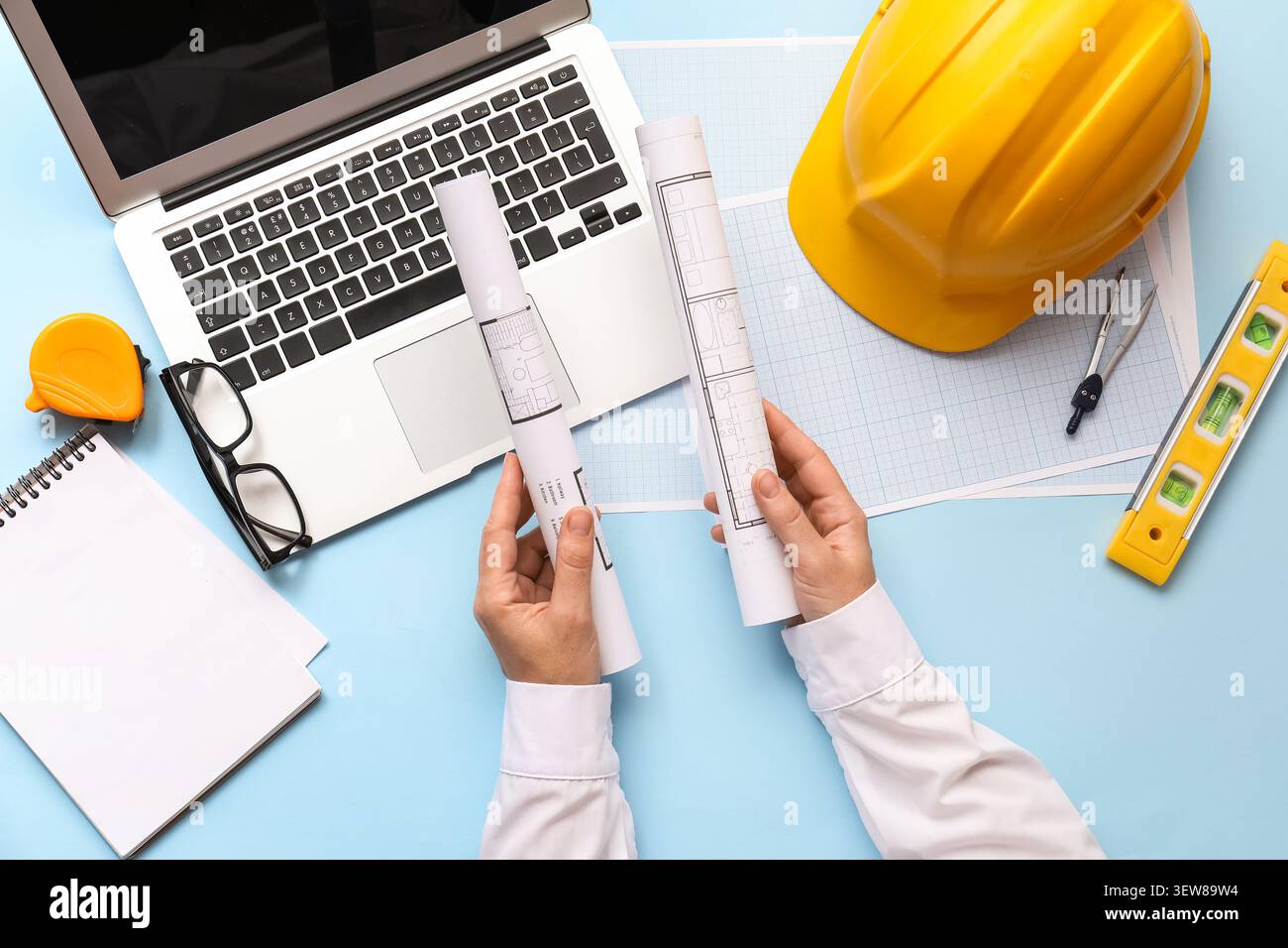 Architect reviewing blueprints with laptop and construction tools Stock Photo