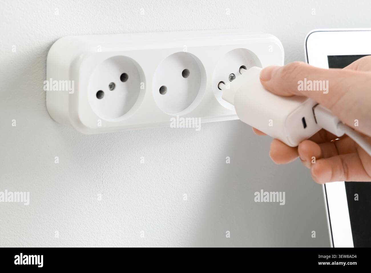 Hand plugging charger into wall socket Stock Photo