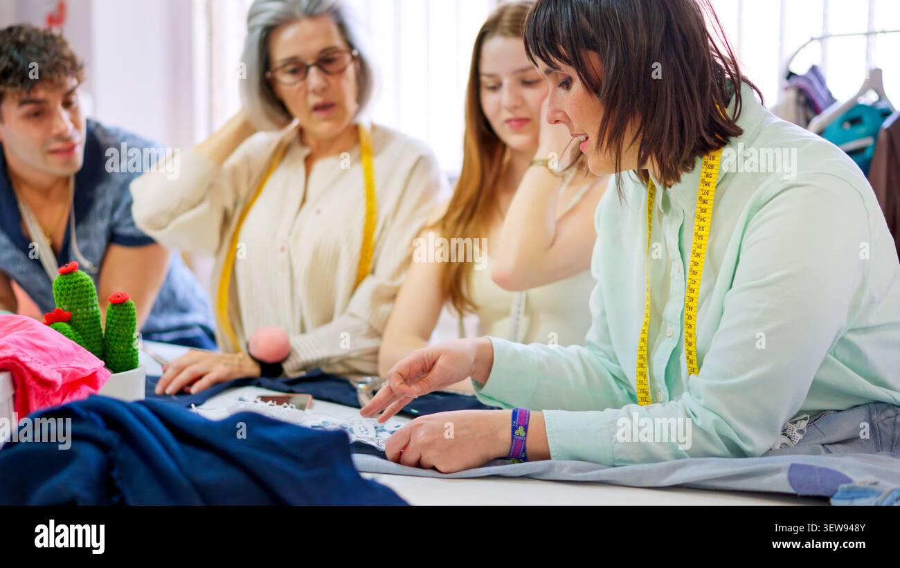 Tailor instructing students crafting fabric in sewing workshop class Stock Photo
