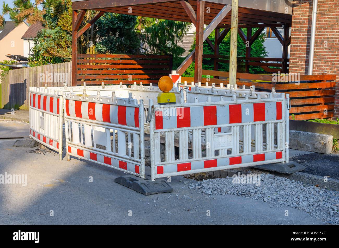 White and red construction barriers with warning light blocking a road. Stock Photo
