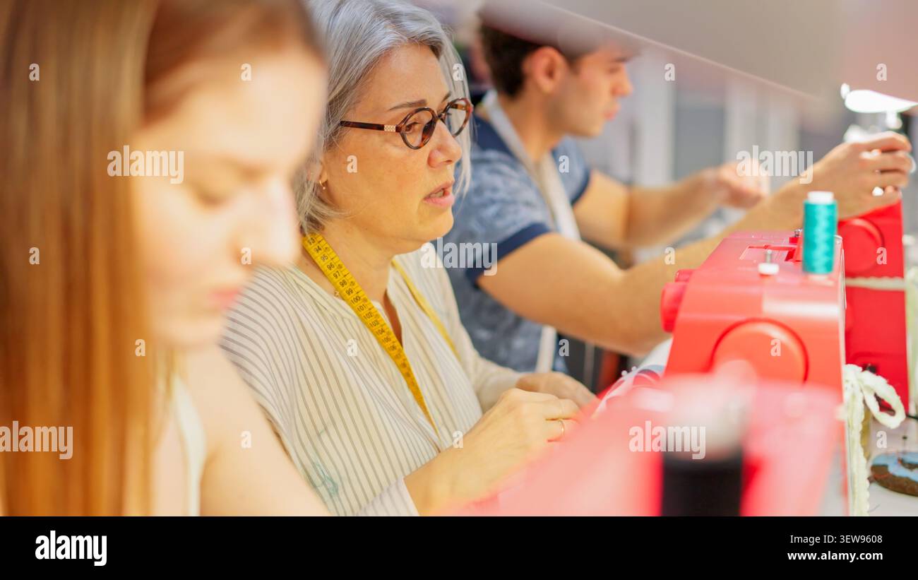 Adults learning sewing skills in textile workshop Stock Photo