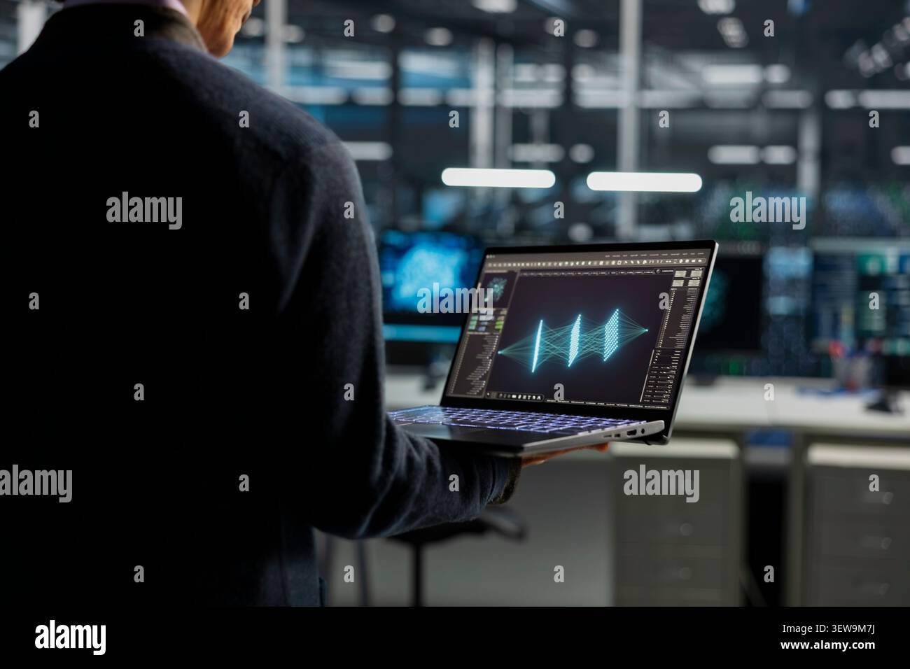Data center technician uses a desktop computer in a data center to manage AI systems and optimize server infrastructure. Stock Photo