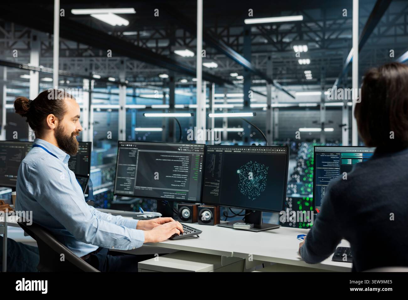Data center team uses a desktop computer in a data center to manage AI systems and optimize server infrastructure. Stock Photo