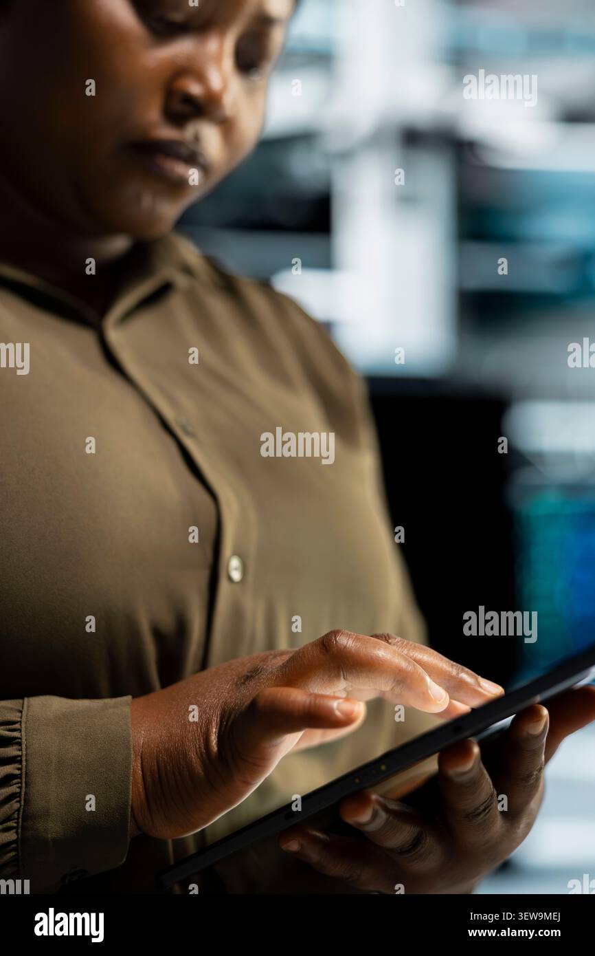 Software developer uses a digital tablet in a data center to run hardware diagnostics and maintain operational stability. Stock Photo