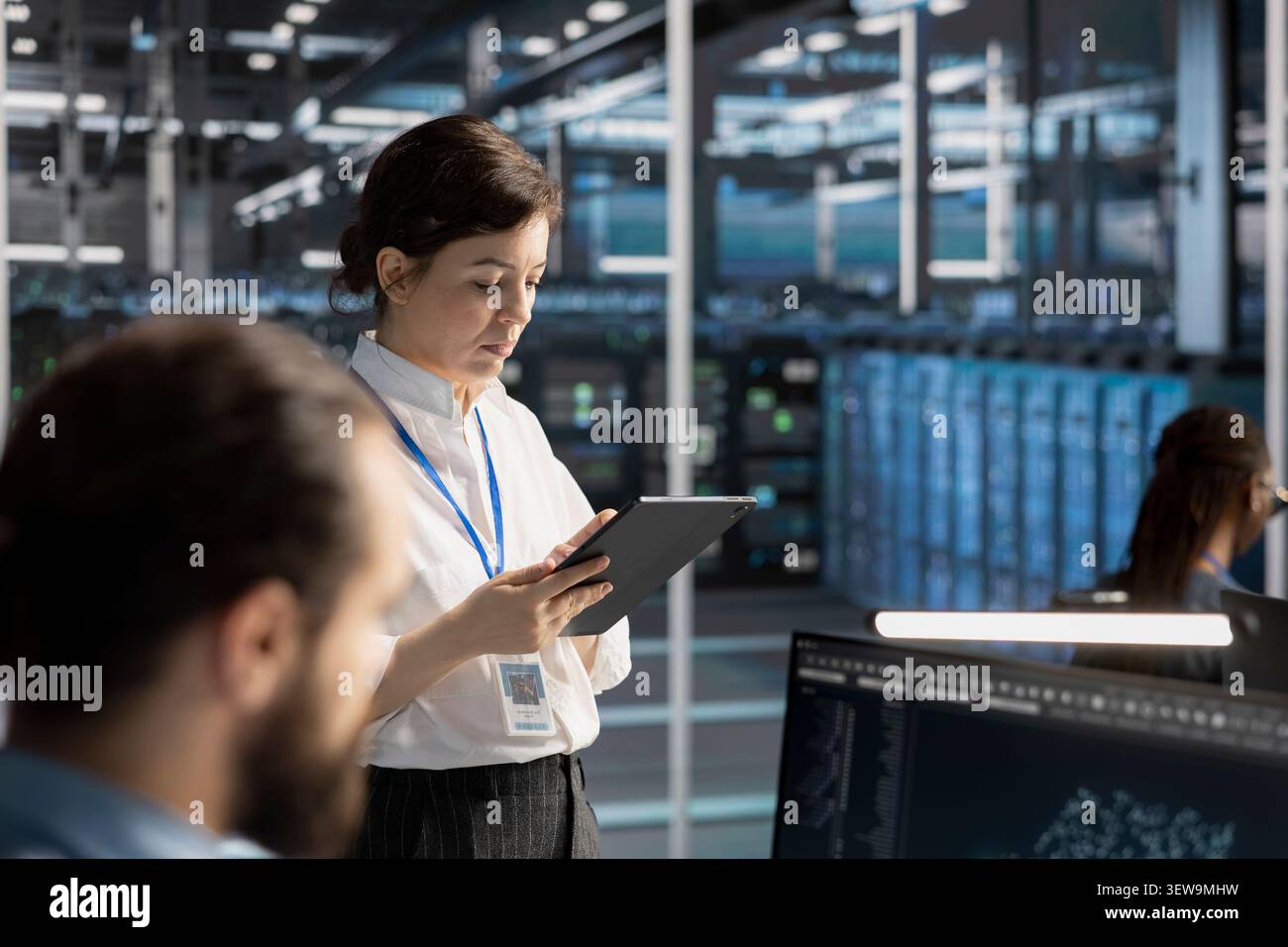 Engineering team uses a digital tablet in a data center to manage AI virtualization and optimize server infrastructure. Stock Photo
