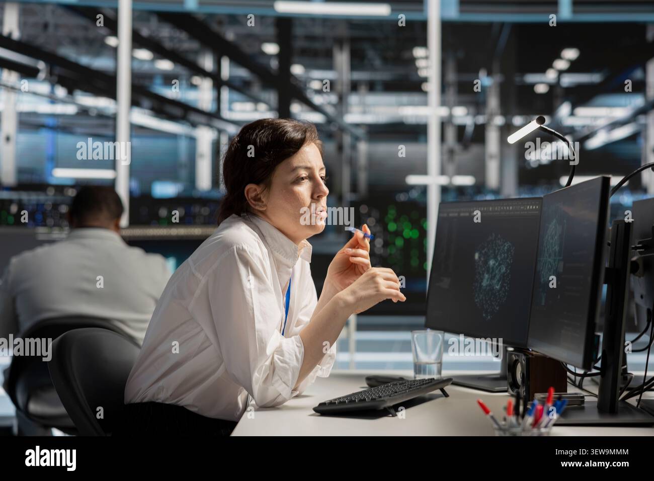 System administrator uses a digital device in a data center to manage AI simulation and optimize server infrastructure. Stock Photo