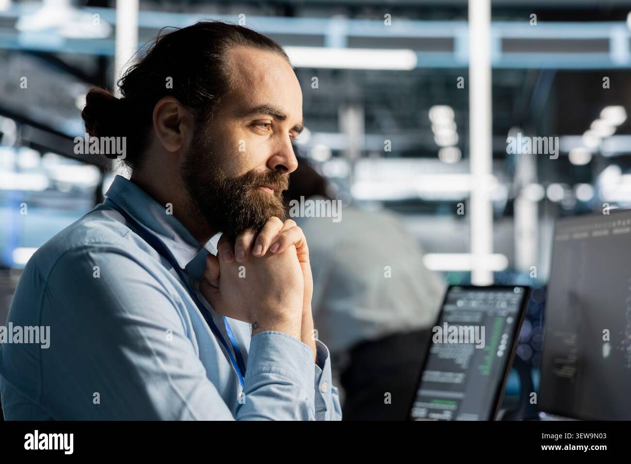 Computer scientist uses a desktop computer in a data center to manage AI systems and optimize server infrastructure. Stock Photo