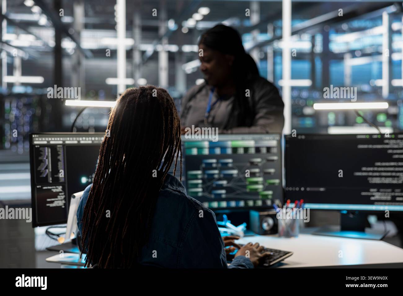 System administrator uses a desktop computer in a data center to manage AI visualization and optimize server infrastructure. Stock Photo