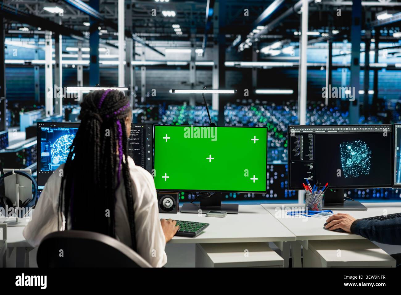 Data center technician uses a chroma key computer to review server hardware stability and infrastructure maintenance. Stock Photo