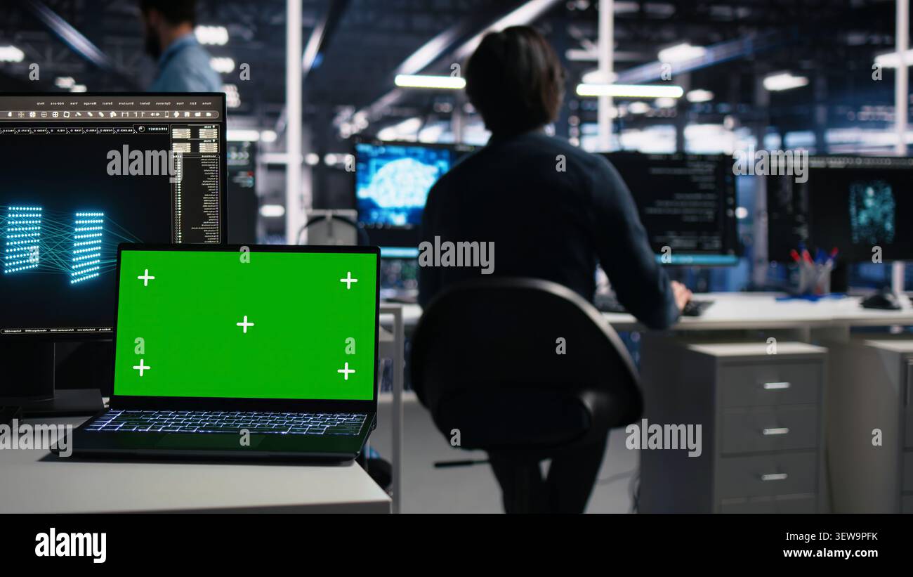Software developer uses a green screen laptop to manage AI systems, machine learning workflows and server performance. Stock Photo