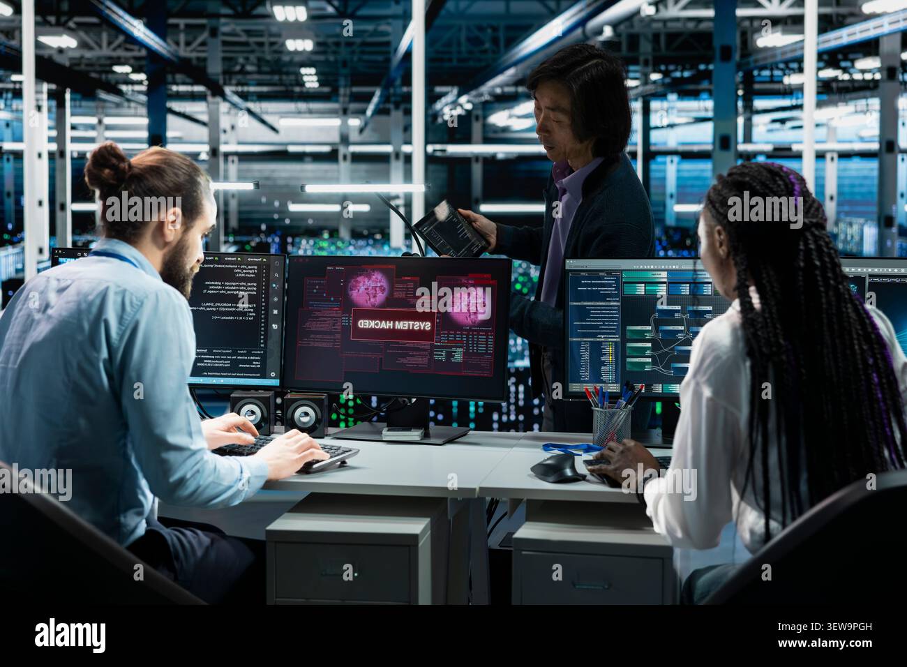 Engineering team reviews a security breach alert for a zero-day vulnerability inside a high-tech server room. Stock Photo