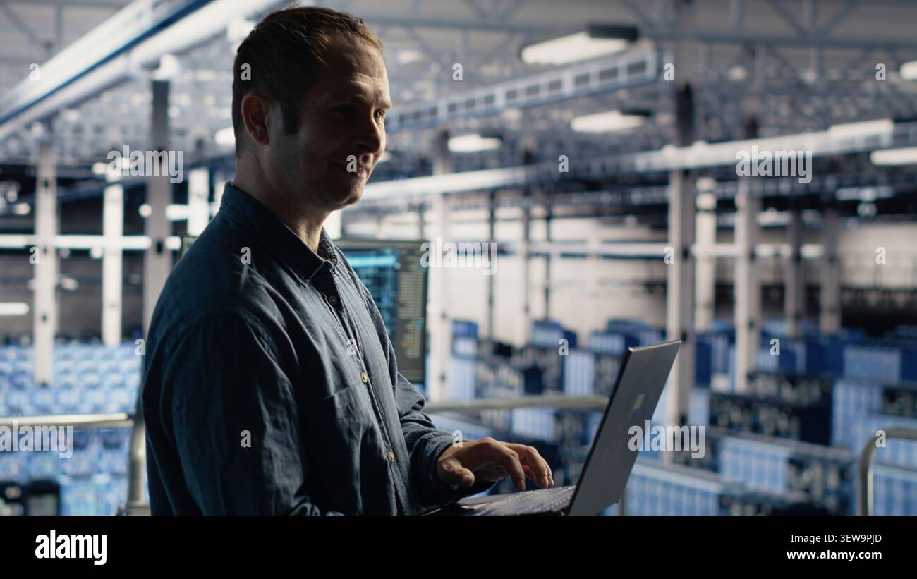 Data center technician monitors AI systems and machine learning workloads on a laptop inside a high-tech server facility. Stock Photo