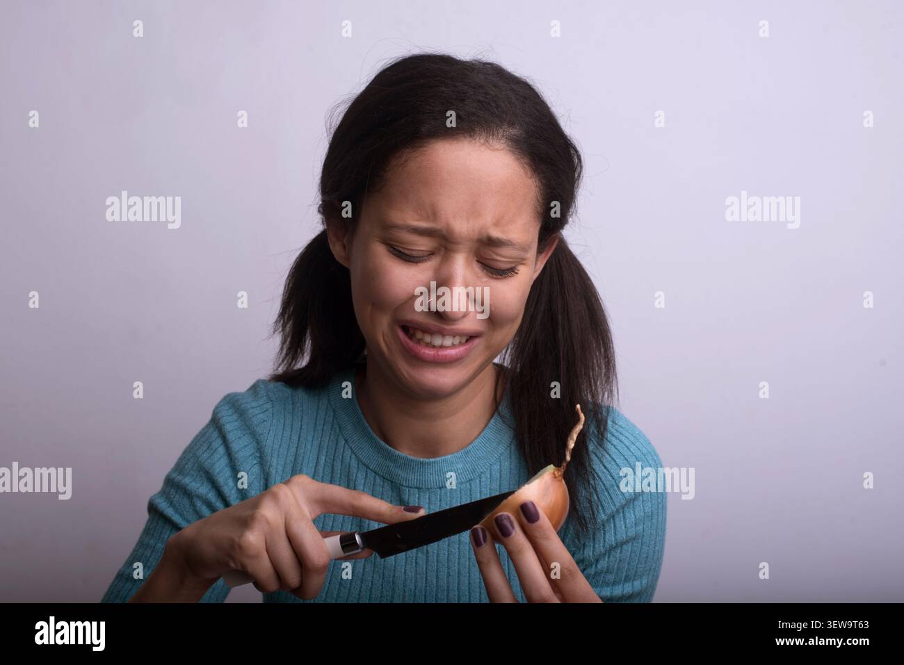 Young woman crying while cutting an onion Stock Photo