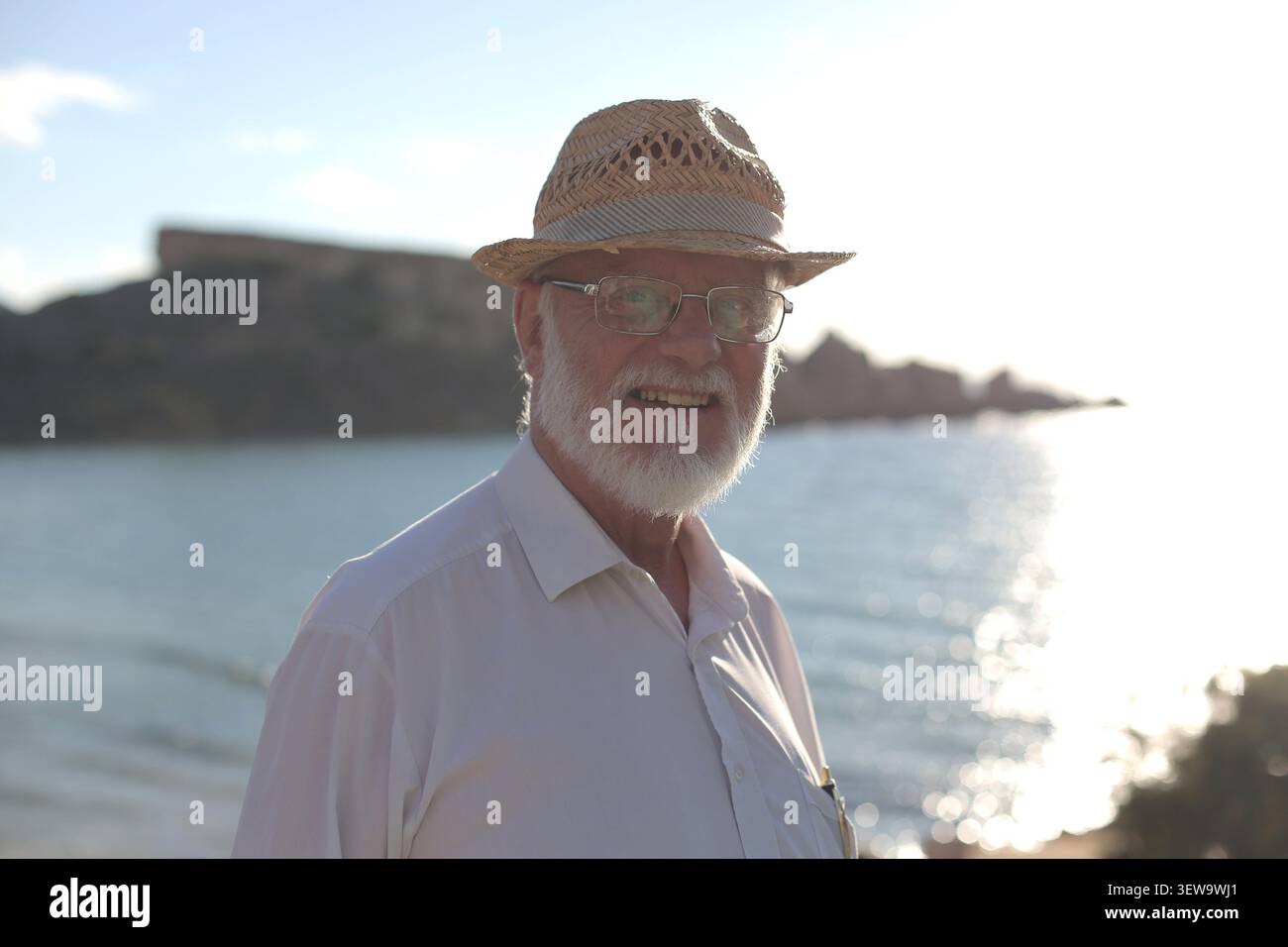 Elderly man in a straw hat smiles by the sea Stock Photo