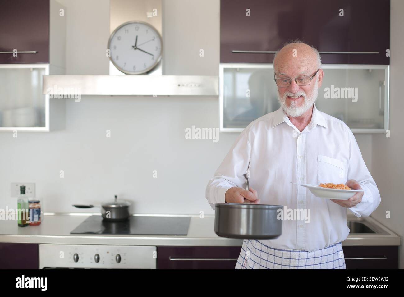 Happy senior man serving pasta for dinner at home Stock Photo