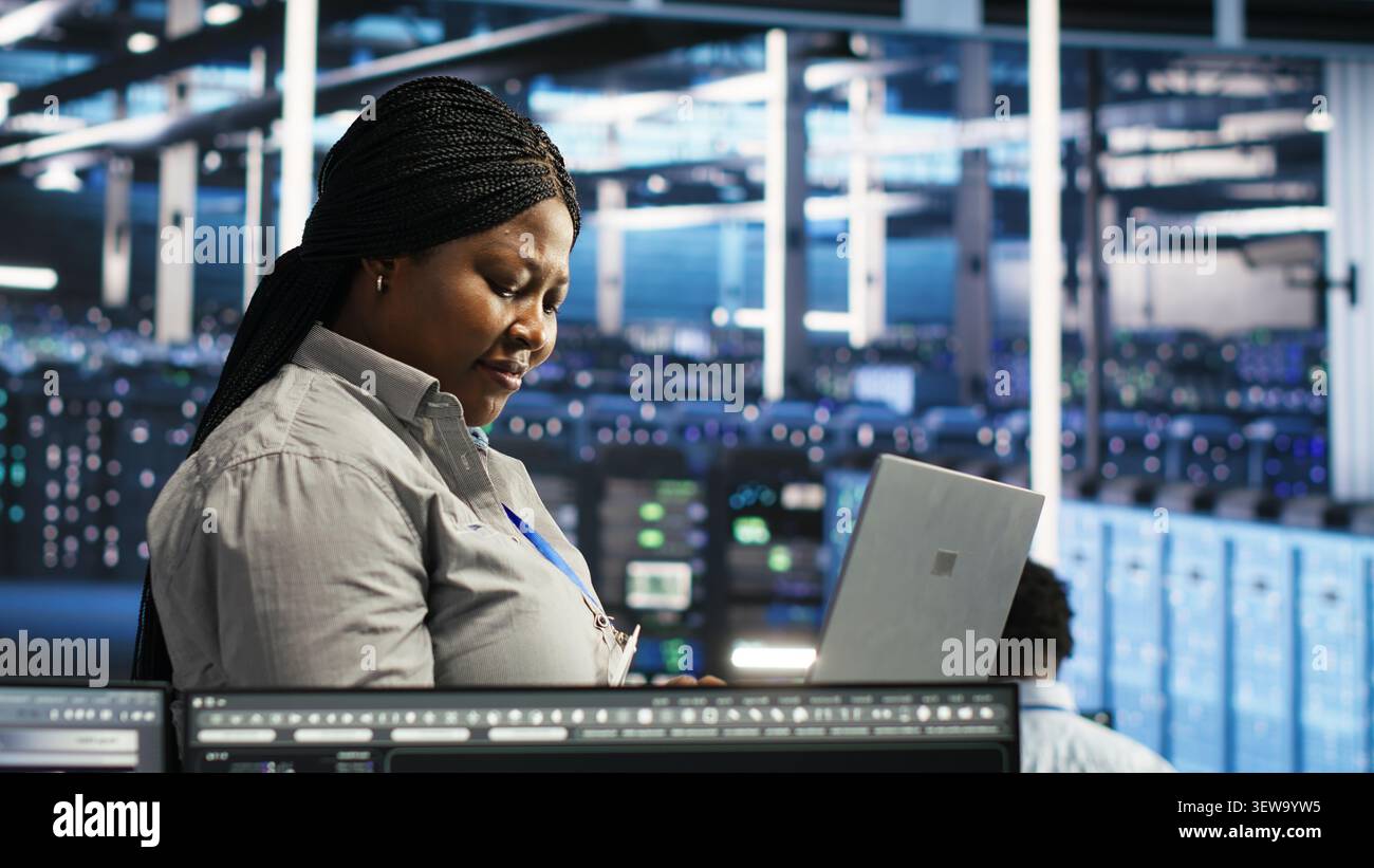Data center administrator uses laptop node tree software to review analytics and identify equipment issues. Stock Photo
