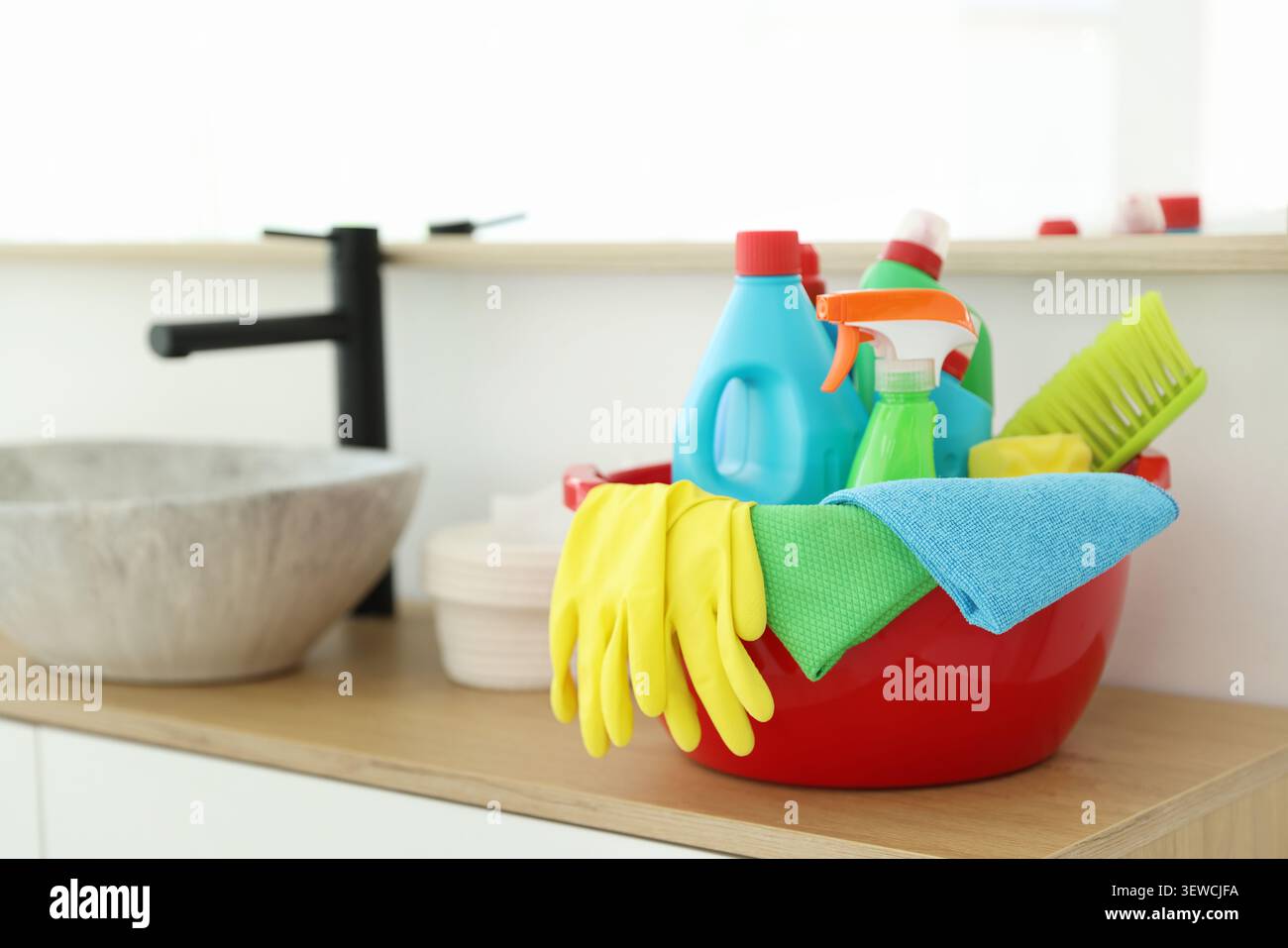 Red plastic basin with cleaning products and supplies on counter in bathroom Stock Photo