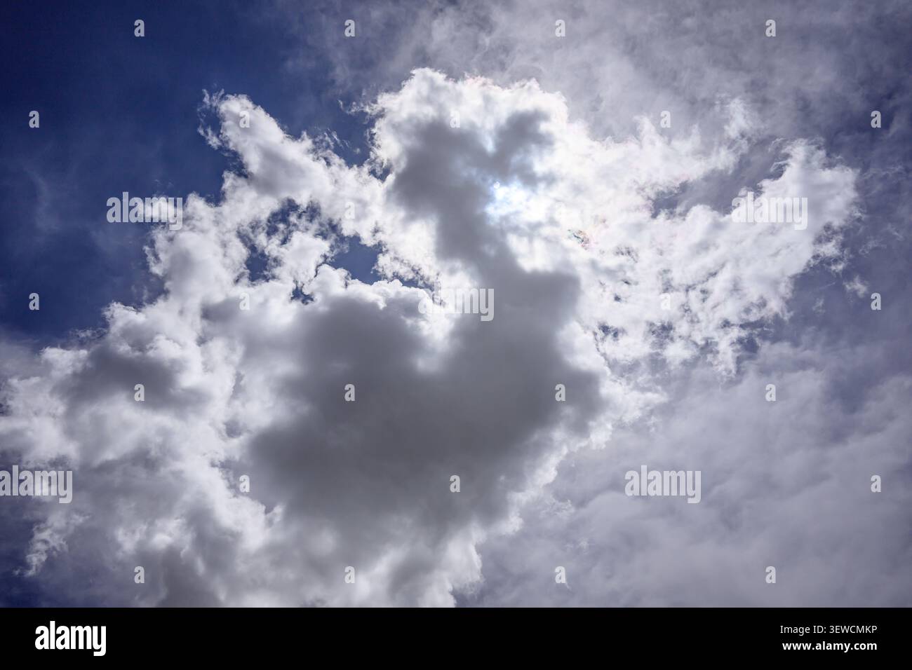 Dramatic sky with fluffy white clouds against deep blue background Stock Photo