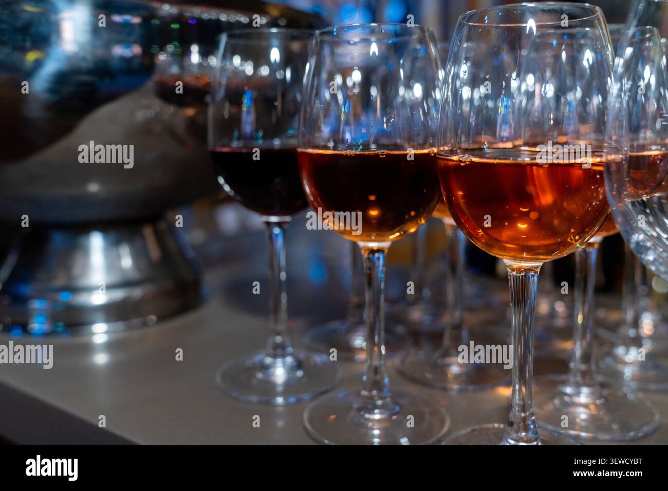 Rows of elegant red wine glasses filled with ruby wine at a tasting. Sophisticated hospitality, fine dining, and winery culture backdrop. Stock Photo