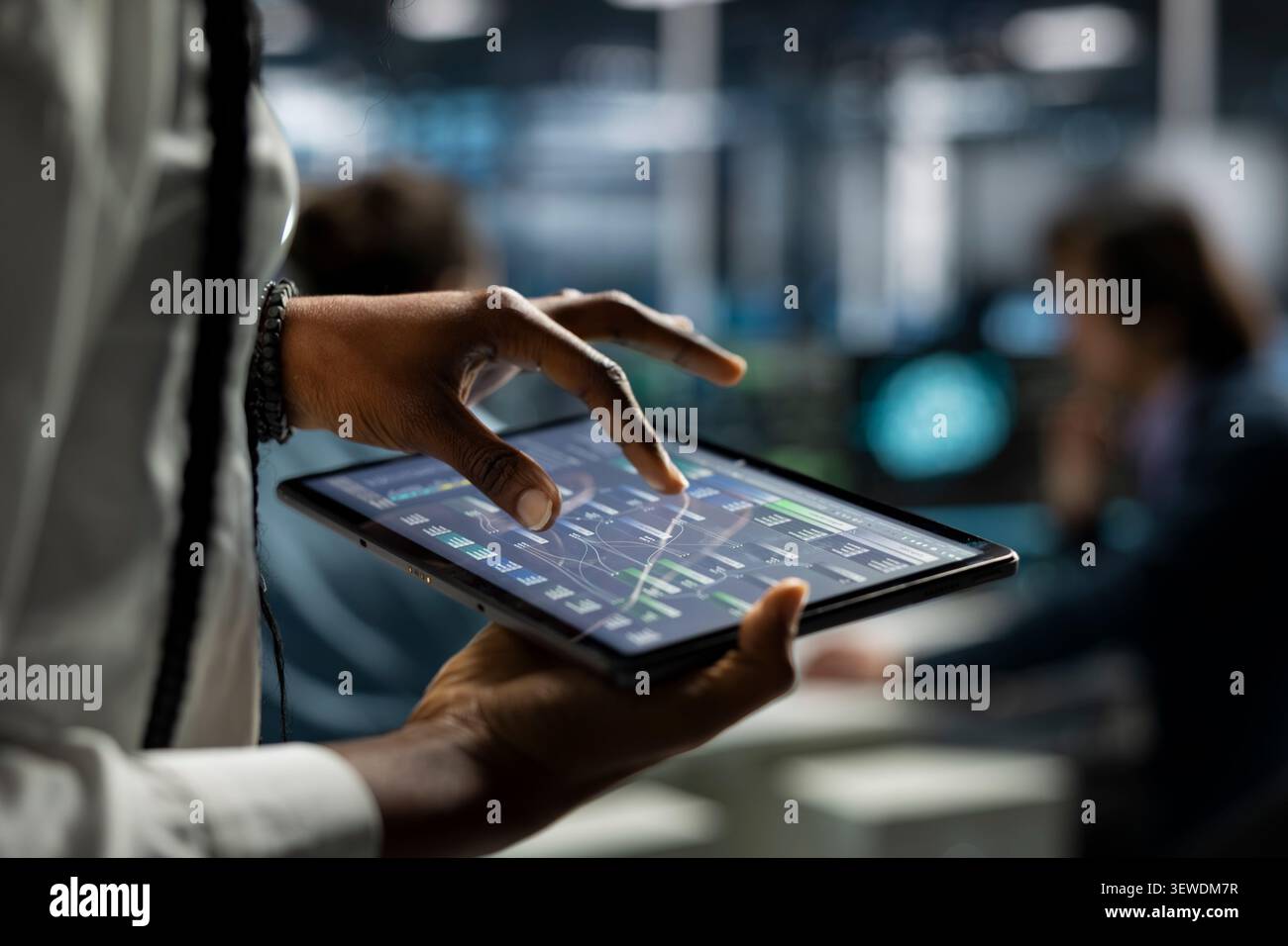 Computer scientist uses a digital tablet in a data center to deploy software updates, configure hardware, and support reliable operations. Stock Photo